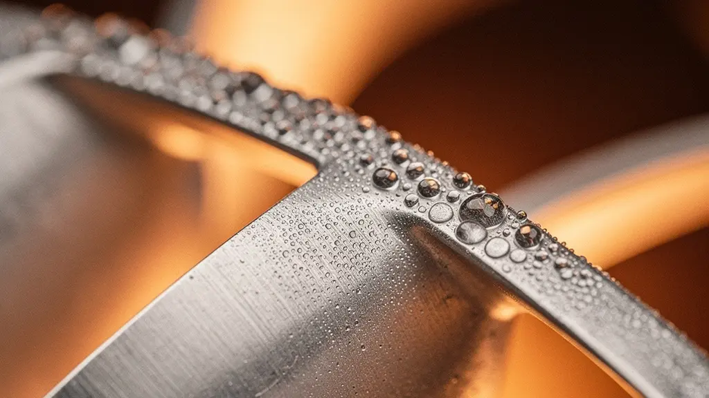 Gros plan macro sur les pales métalliques d'un ventilateur industriel de refroidissement couvertes de fines gouttelettes d'eau condensée